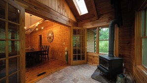 A log cabin interior with a dining area, a fireplace, and a large window.
