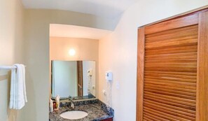 Une salle de bain avec un lavabo, un miroir, un porte-serviettes et une porte en bois.