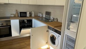 Une cuisine compacte équipée d’un lave-linge et d’un sèche-linge intégrés, d’un four à micro-ondes, d’un grille-pain et d’un évier.