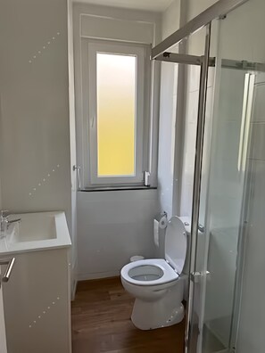 Ein Badezimmer mit Toilette, Waschbecken und einer Duschkabine aus Glas.