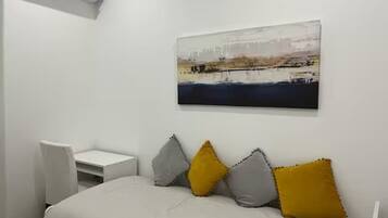 Ein Schlafzimmer mit Bett, Schreibtisch, Klimaanlage und einem Bild an der Wand.