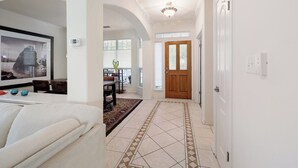 A hallway with a dining area, a white couch, and a patterned floor. - Rosey Bouldin Home + Minutes to DT - Adelaide! (Austin)