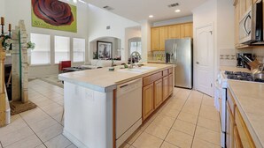 A spacious kitchen with a large island, wooden cabinets, and a stainless steel refrigerator. - Rosey Bouldin Home + Minutes to DT - Adelaide! (Austin)