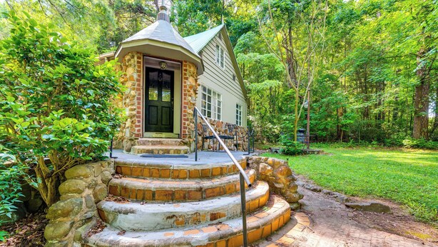 Una escalera de piedra que lleva a una casa con puerta verde, rodeada de abundante vegetación.