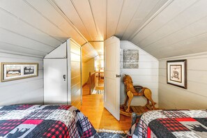 Een slaapkamer met twee bedden, een houten schommelpaard en een trap naar een vide.
