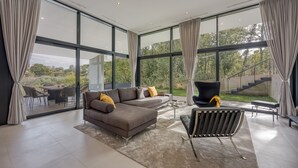 A modern living room with a sectional sofa, a black chair, and a coffee table. Large windows offer a view of the outdoors. - House K2 (Kanfanar)