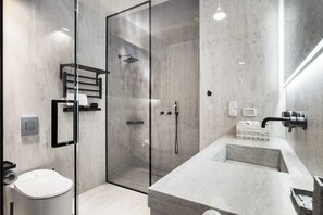 A modern bathroom with a glass-enclosed shower, a white toilet, and a large sink with a marble countertop. - Top TLV Grand Suites (Tel Aviv)