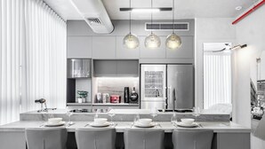A modern kitchen with a central island, bar stools, and pendant lighting. - Top TLV Grand Suites (Tel Aviv)