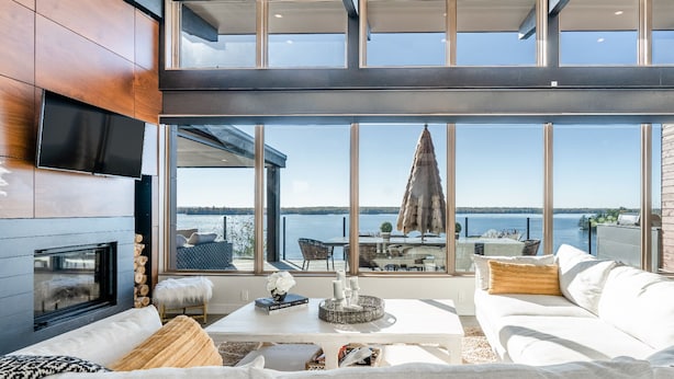 Een moderne woonkamer met een open haard, grote ramen en uitzicht op het water.