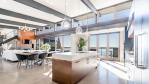 Een moderne keuken met een centraal eiland, grote ramen en uitzicht op de omgeving.