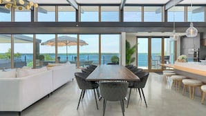 Een modern interieur met een eethoek, keuken en grote ramen met uitzicht op een wateroppervlak.