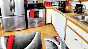 A compact kitchen with a refrigerator, oven, toaster, coffee maker, and wooden cabinets. - Stay right in the heart of Long Beach, WA — steps from the ocean! (Long Beach)