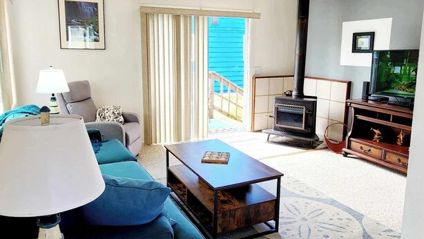 A living room with a sofa, a coffee table, a lamp, a fireplace, and a television. - Stay right in the heart of Long Beach, WA — steps from the ocean! (Long Beach)