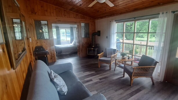 L’intérieur d’un chalet accueillant, avec un plancher en bois, un canapé, des fauteuils en osier, une table et une cheminée.