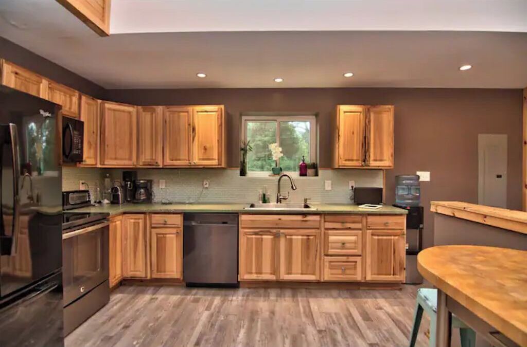 A modern kitchen with wooden cabinets, stainless steel appliances, and a large window.
