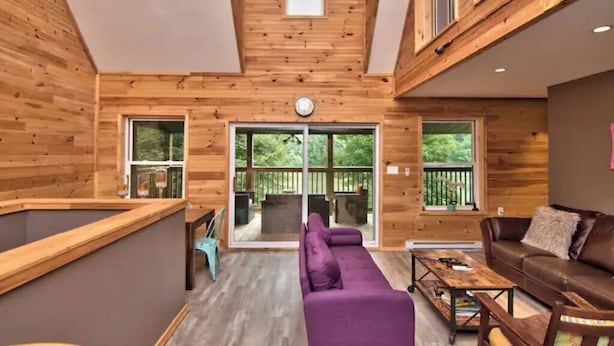 A wooden interior with a sofa, a coffee table, and a leather couch. - Riverfront Retreat For Kayaking, Fishing and Hot Tub (Falls)