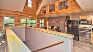 A spacious kitchen with high ceilings and wooden beams, featuring modern appliances and a large island. - Riverfront Retreat For Kayaking, Fishing and Hot Tub (Falls)