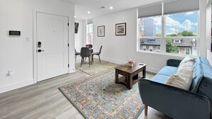 A modern living room with a sofa, a coffee table, and a dining area with chairs and a table.