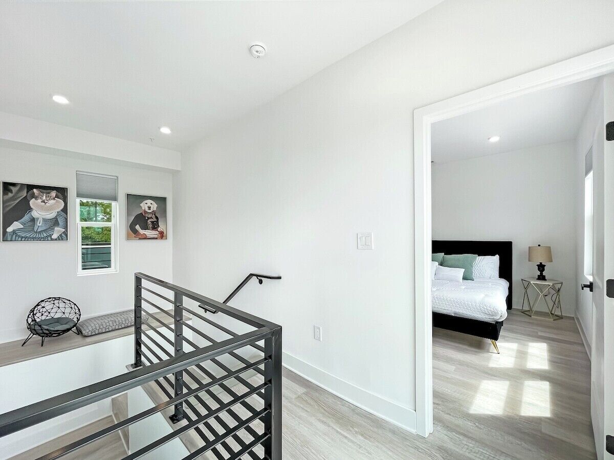 A modern bedroom with a bed, a nightstand, and a chair. There is a staircase leading to another room.