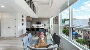 Ein modernes Apartment mit Essbereich, Küche und großen Fenstern mit Blick auf die Stadt.