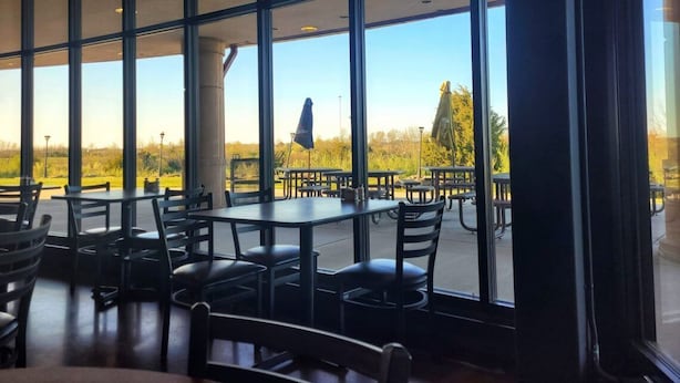 An indoor dining area with large windows, tables, and chairs.