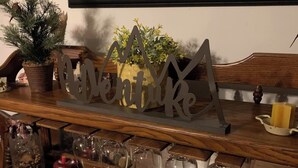 A wooden bar counter with a decorative sign, glassware, and a potted plant.