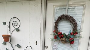 A white door with a wreath, potted plants, and a doormat.