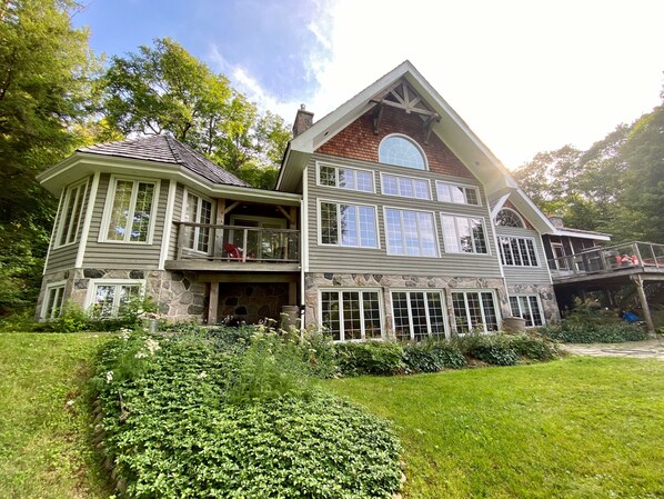 A large, multi-story house with a stone facade, multiple balconies, and a spacious front yard. - Welcome to this 4,200 sq. ft, 7 bedroom Cottage on Lake of Bays! Sleeps 16 (Baysville)