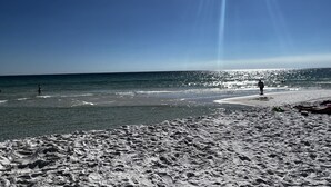A beach with a clear sky, calm sea, and a few people walking. - Rare end unit at the Palms of Destin w/ 2 King beds Steps from the Pool
 (Destin)