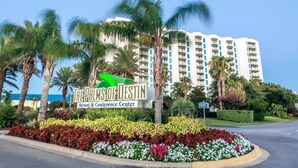 A sign for The Palms of Destin Resort & Conference Center, surrounded by palm trees and a landscaped flower bed. - Rare end unit at the Palms of Destin w/ 2 King beds Steps from the Pool
 (Destin)