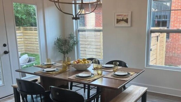 A dining area with a wooden table, black chairs, a bench, and a chandelier. - Cozy 2-Story House in Historic Downtown Wilmington. Walk to weddings & concerts! (Wilmington)