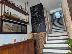 Et barområde med træhylder, en tavle med menu, og en trappe.