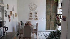 A dining area with a glass table, chairs, and a decorative wall piece.