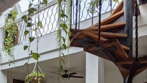 A spacious interior with a wooden staircase, hanging plants, and a ceiling fan. - Walled City 2-bedroom 2-bath Condo with Patio (Cartagena de Indias)