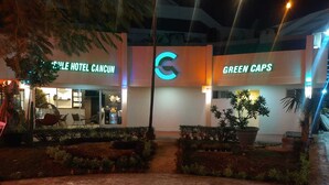The exterior of the Cycle Hotel Cancun and Green Caps, featuring a modern design with illuminated signage and well-maintained landscaping. - Green Caps Cancún Hospedaje (Cancun)