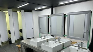 A public restroom with four sinks, mirrors, and trash bins. - Green Caps Cancún Hospedaje (Cancun)