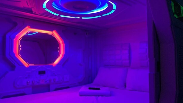A futuristic room with a hexagonal light fixture, a control panel, and a bed. - Green Caps Cancún Hospedaje (Cancun)