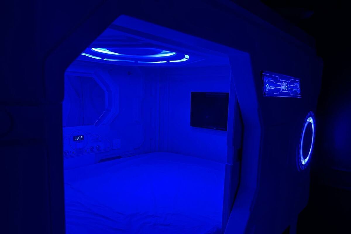 A room with a bed, a control panel, and a small window.