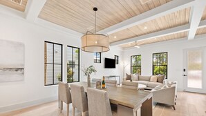Un salón espacioso con una mesa de comedor de madera, sofás color beige y ventanas grandes que dejan entrar luz natural.