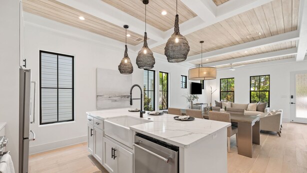 Una cocina moderna con una isla central, electrodomésticos de acero inoxidable e iluminación colgante.
