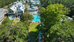 Un resort con varias edificaciones, una piscina central y abundante vegetación.