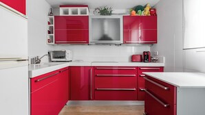Une cuisine moderne avec des meubles rouges, un plan de travail blanc et une hotte en acier inoxydable.