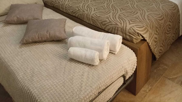 A neatly made bed with a patterned bedspread and pillows, a bedside table with a lamp, and a wall art piece above the bed. - Cornflower House (San Benedetto del Tronto)