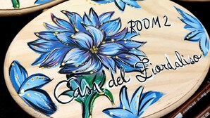 Three wooden plaques with floral designs and room labels. - Cornflower House (San Benedetto del Tronto)