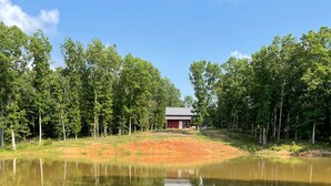 Un cadre paisible au bord d’un lac, avec un petit chalet et une forêt dense.