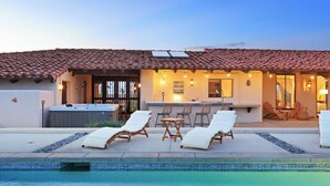 Zona junto a la piscina con sillones de descanso, jacuzzi y bar con guirnaldas de luces.