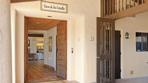 Entrada de un hotel con un cartel que dice "Casa de la Estrella", suelo de baldosas y una puerta de madera con un panel decorativo.