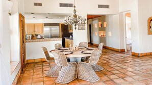 Un comedor amplio con techo de madera, candelabro y suelo de baldosas.