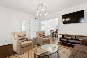 Relax in this stylish living room with a glass coffee table, TV stand, and comfortable armchairs.