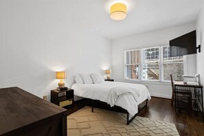 Relax in a serene space with a large bed, bedside table, and desk, offering a city view from the large window.